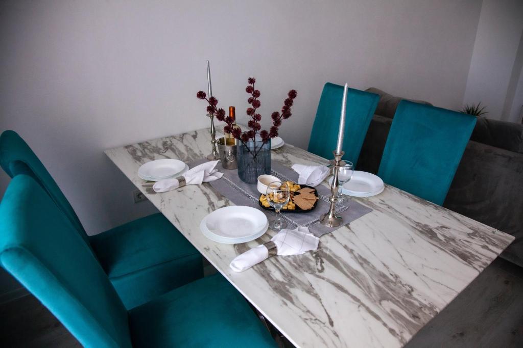 a dining table with blue chairs and a marble table with plates at Noah Residence in Alba Iulia