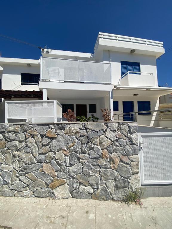 a white house with a stone wall at Green Bay Area Apartment in Protaras