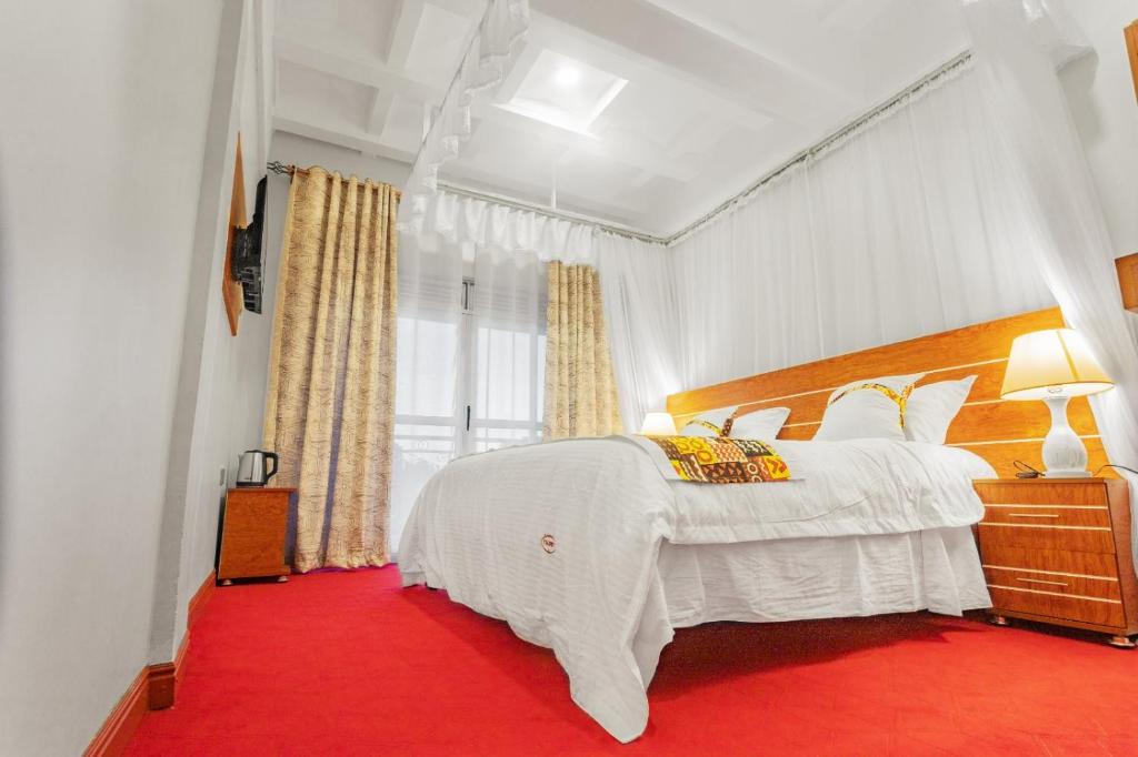 a bedroom with a white bed with a red carpet at Ambrosia Heights in Entebbe