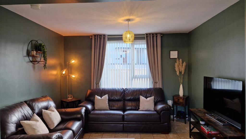 sala de estar con sofá de cuero y TV en Westland Retreat - Magherafelt - Mid Ulster - NITB Approved, en Magherafelt