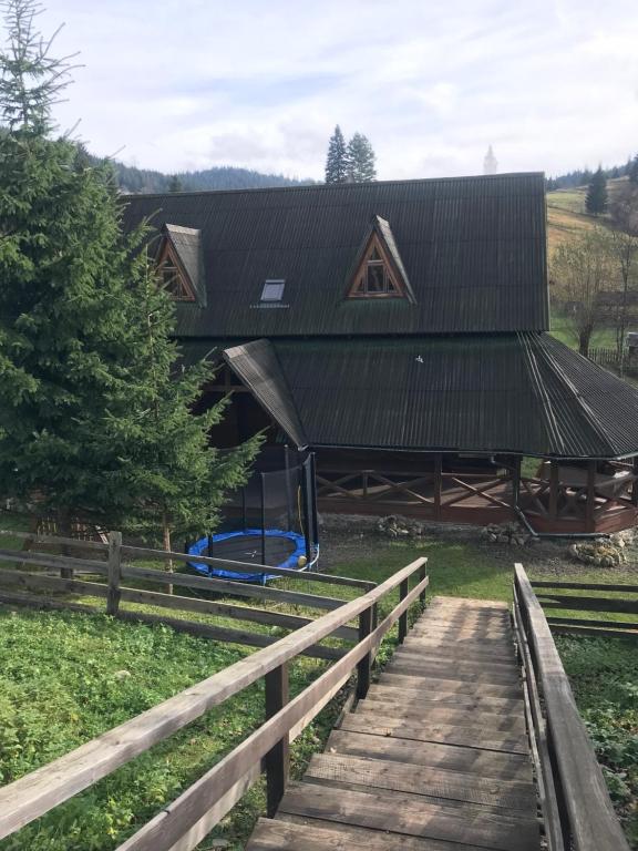 a wooden bridge leading to a house with a gambrel roof at Trembita in Yablunytsya