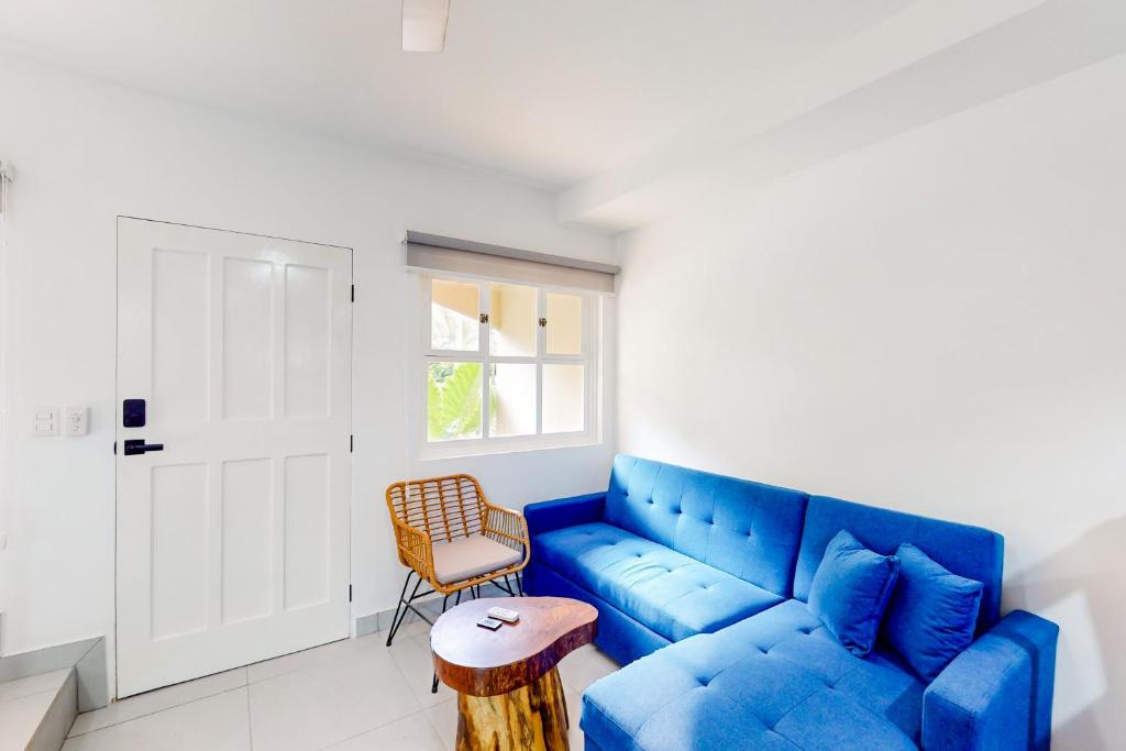 Una sala de estar con un sofá azul y una silla. en Villa Verde I - 3, en Tamarindo