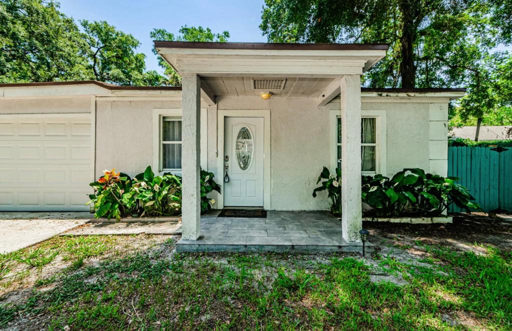 a white house with a porch and a door at Beautiful Pool House in Old Seminole Heights! in Tampa
