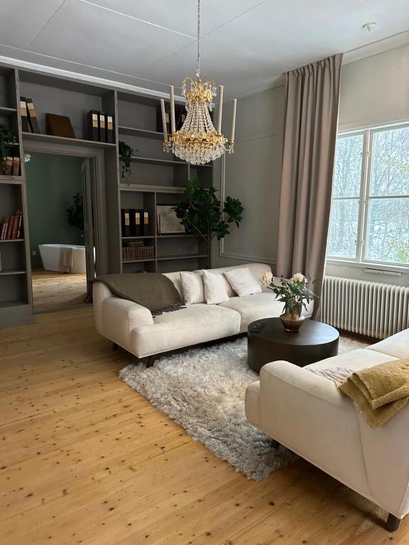 a living room with white couches and a chandelier at Pastors Prästgården in Norberg