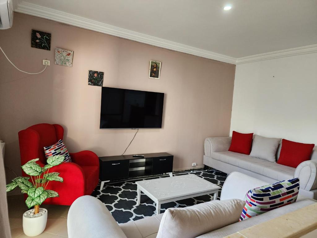 a living room with red furniture and a flat screen tv at Duplex bien equipe securise avec jardin et veranda in La Marsa