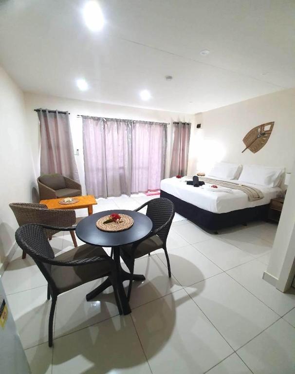 une chambre d'hôtel avec un lit, une table et des chaises dans l'établissement Wolfgramm Beachfront Motel, à Utungake