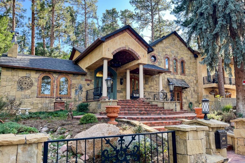 a stone house with a black fence in front of it at Mediterranean Mountain Memories in Colorado Springs
