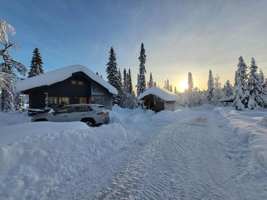 a house covered in snow with a car parked in it at Cozy mountain house in Jämtland in Vallrun