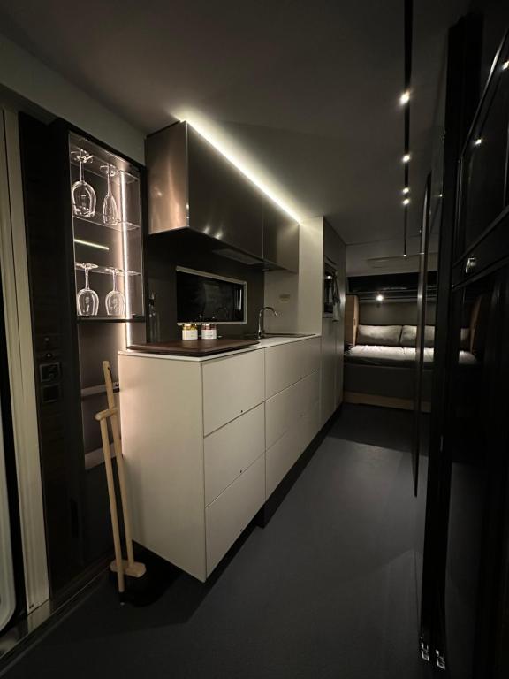 ロヴァニエミにあるSanta`s luxury trailerの白いキャビネット付きのキッチン、ベッド(背景)