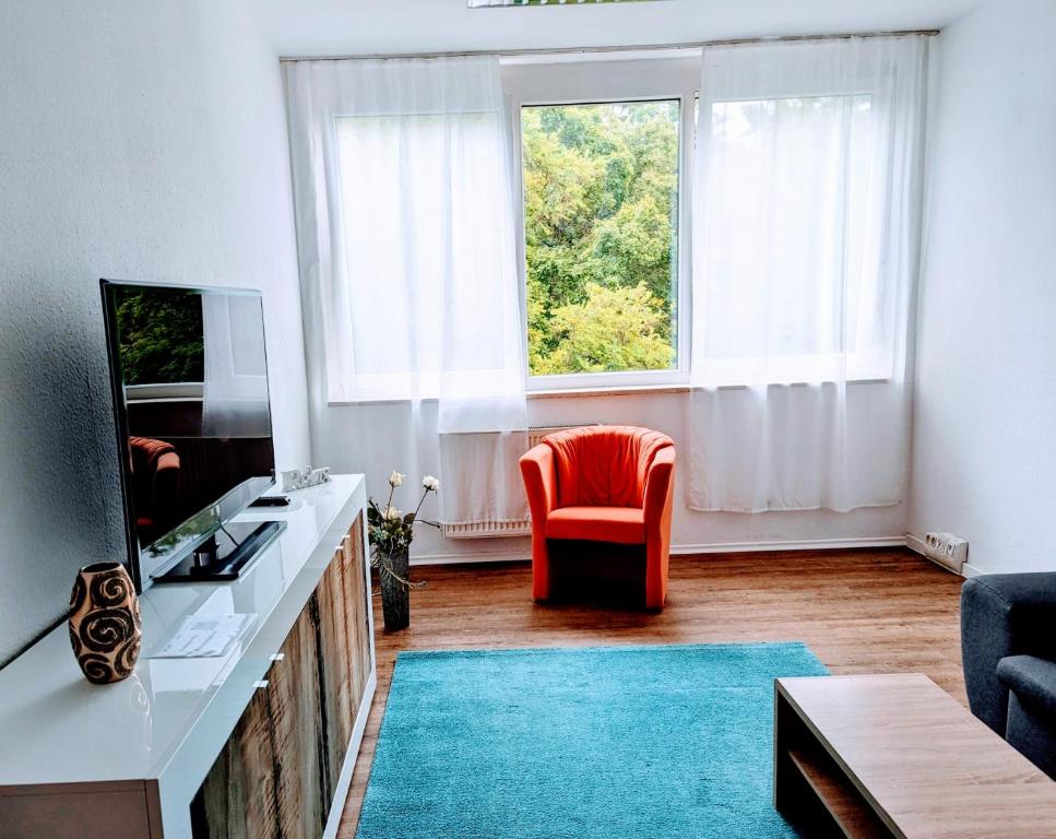 ein Wohnzimmer mit einem roten Stuhl und einem Fenster in der Unterkunft Apartment am Bahnhof und Uniklinik in Mainz