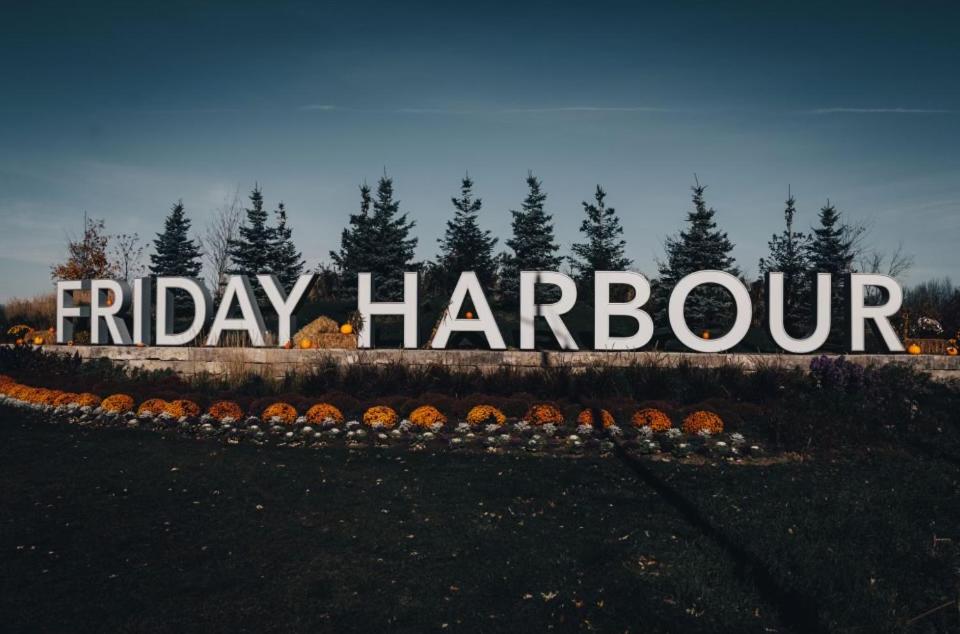 Um sinal que diz sexta-feira Harcourt em frente às árvores em Friday Harbour resort apartment em Innisfil