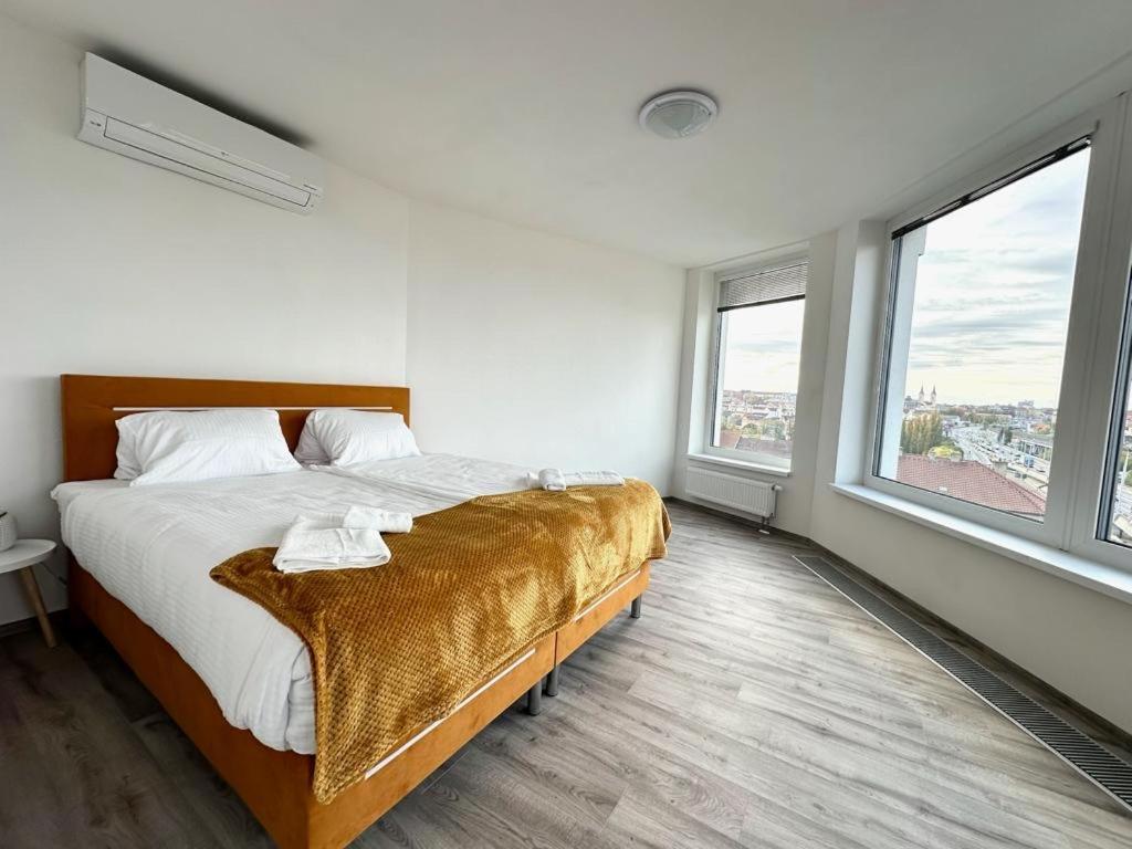 a bedroom with a bed and two windows at Sky Apartments 506 in Plzeň