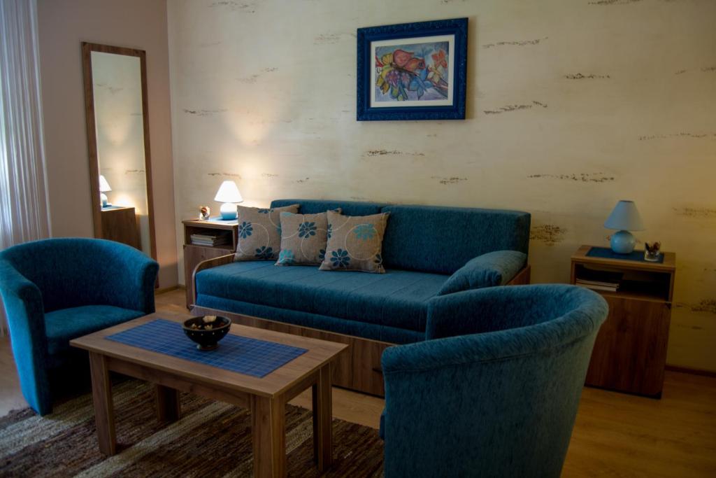 ein Wohnzimmer mit einem blauen Sofa und 2 Stühlen in der Unterkunft Guest House A'storia in Ruma