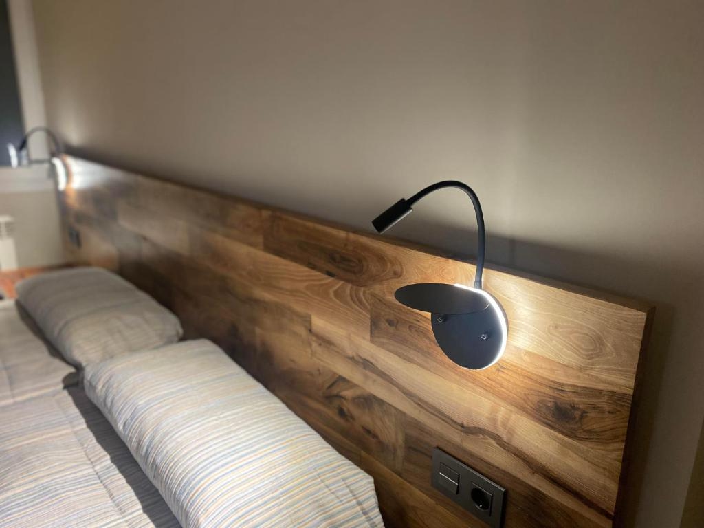 Una cama con un cabecero de madera con una lámpara. en La Rotonda, en Cardona