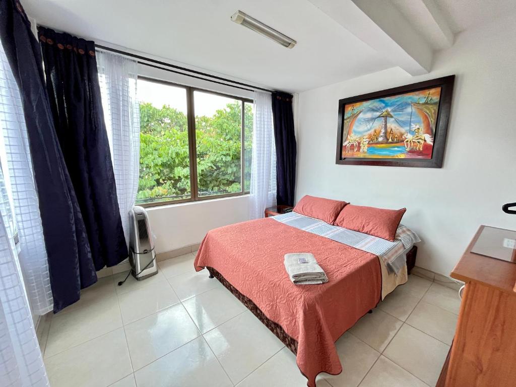 een slaapkamer met een bed en een groot raam bij Lindo Apartaestudio Centro Pereira in Pereira