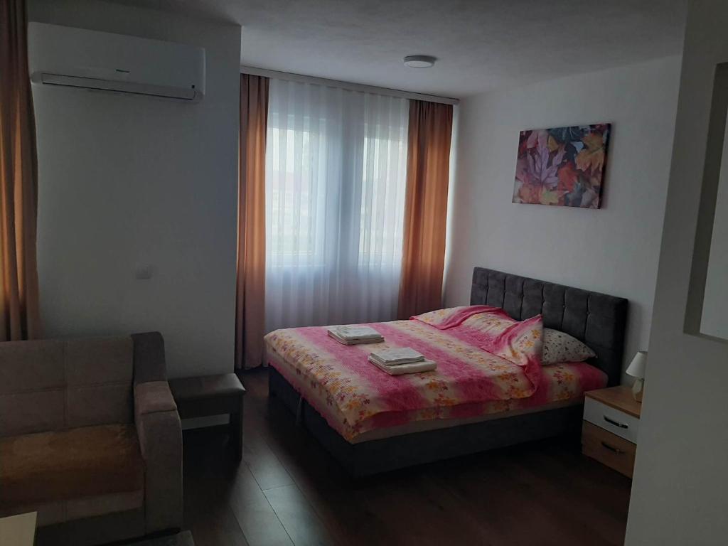 um quarto com uma cama, uma cadeira e uma janela em Apartmani Centar em Sjenica