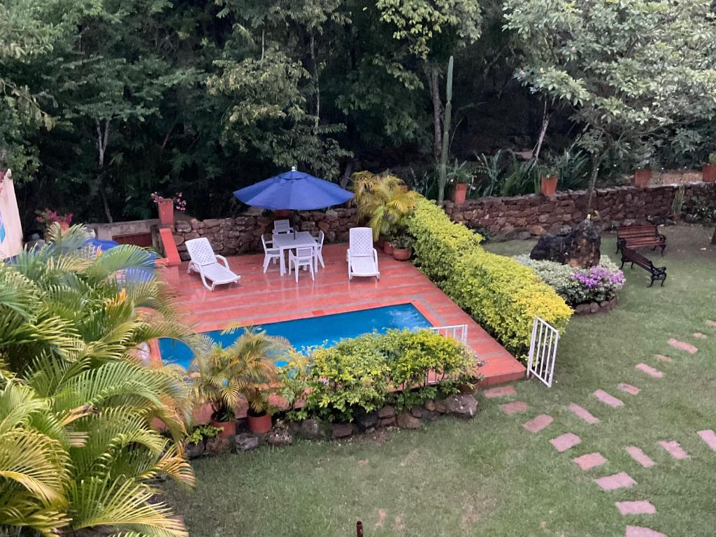 a backyard with a pool and chairs and an umbrella at Casona El Retiro Barichara in Barichara