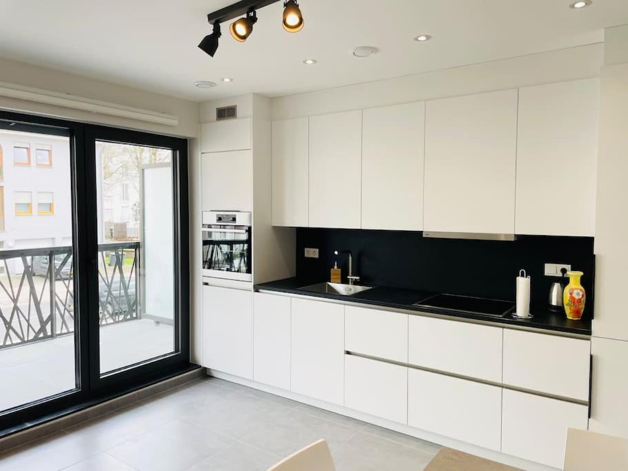 a kitchen with white cabinets and a large window at New One bedroom Flat- Terrace & Parking in Luxembourg
