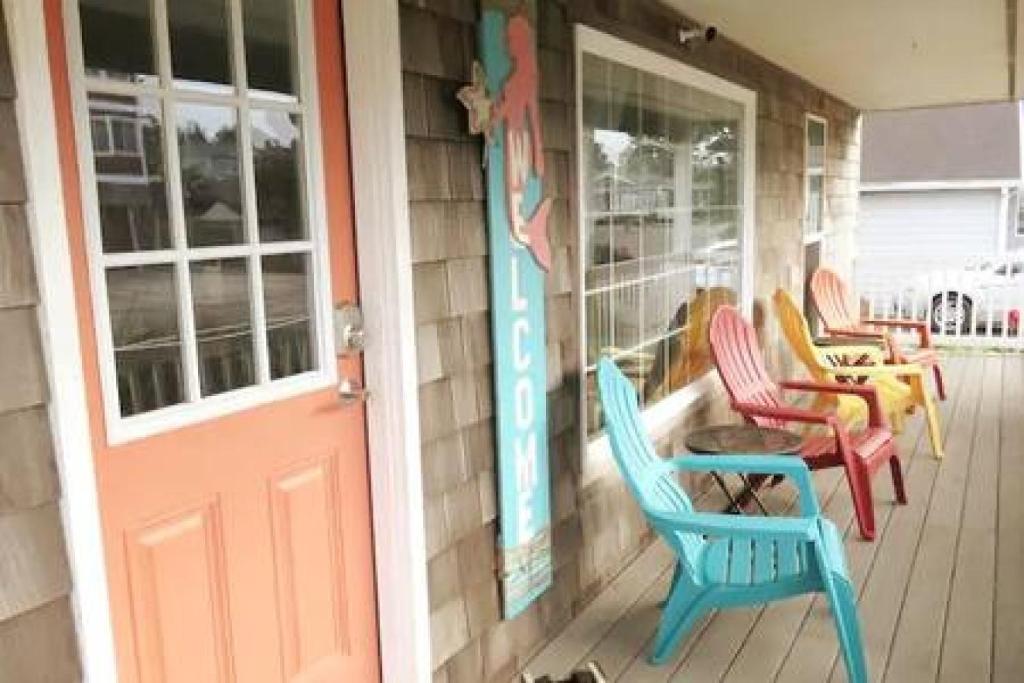 a porch with colorful chairs and a door at Seaside OR- Chic Family Beach Escape & Fast Wi-Fi in Seaside