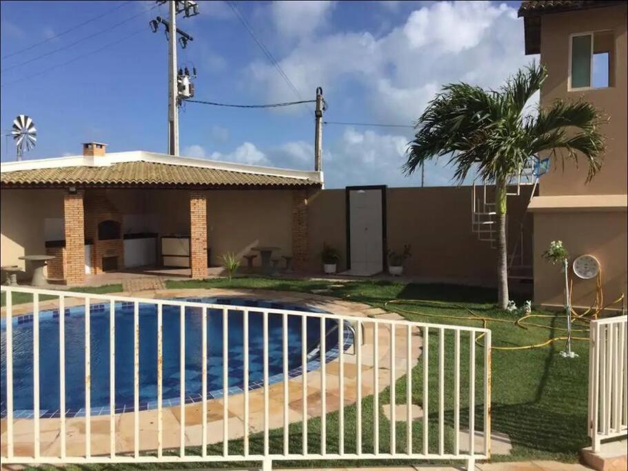a fence in front of a house with a swimming pool at Apto com Ar com vista para praia de Morro Branco - Fortaleza in Beberibe