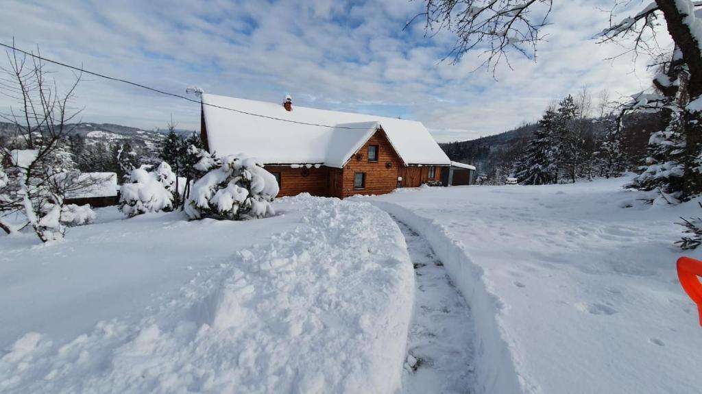 a log cabin covered in snow with a road leading to it at Góralski domek na szczycie in Zwardoń