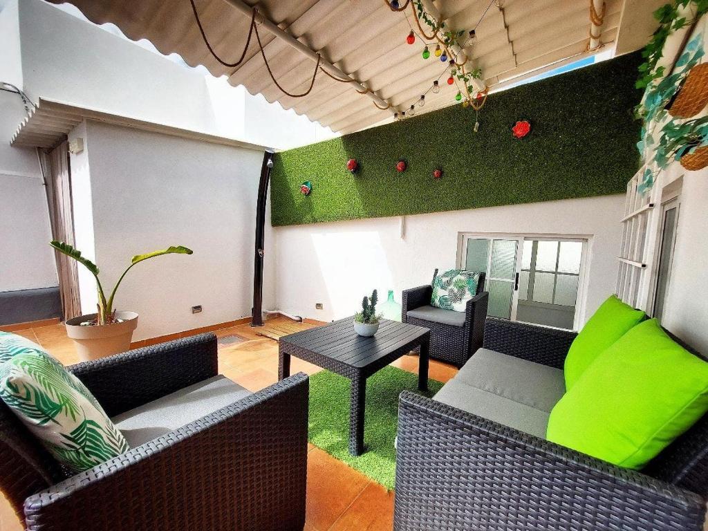 una sala de estar con sofás y una pared verde en Casa BIMBA Agaete con terraza y ducha exterior, en Agaete