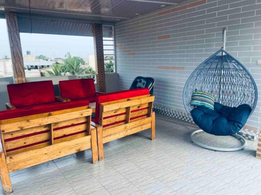 a porch with two benches and a swing at Immeuble Adam in Lomé