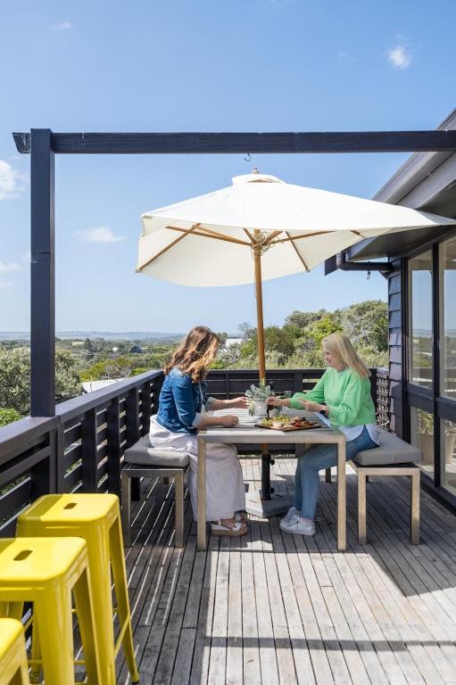 two women sitting at a table under an umbrella at Salty Breeze in Saint Andrews Beach