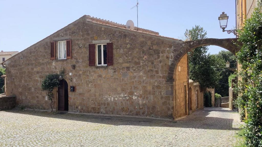 un antiguo edificio de piedra con un arco en una calle en Il Bagolaro, en Tuscania
