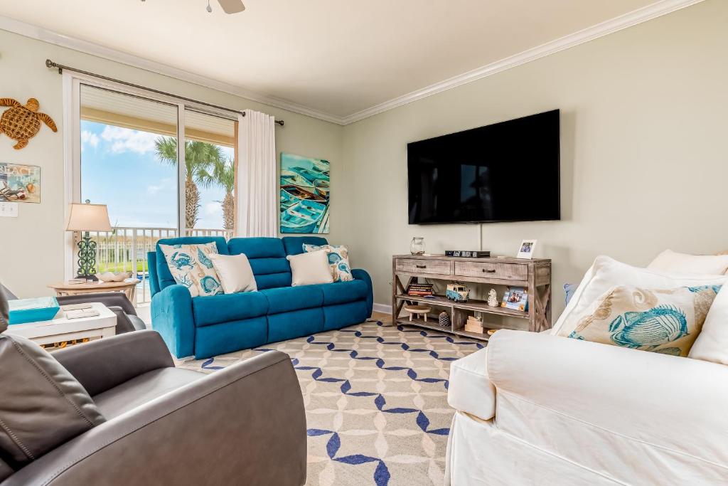 uma sala de estar com um sofá azul e uma televisão em Dauphin Island Beach Club 106A em Dauphin Island