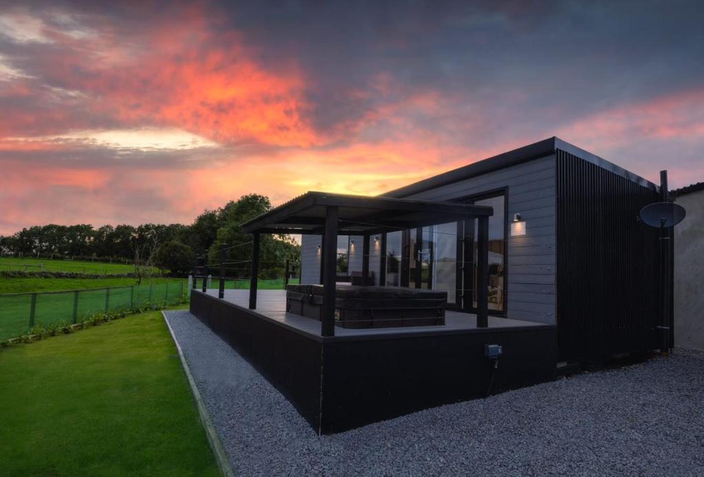 a small black house with a sunset in the background at The Hideout in Newry