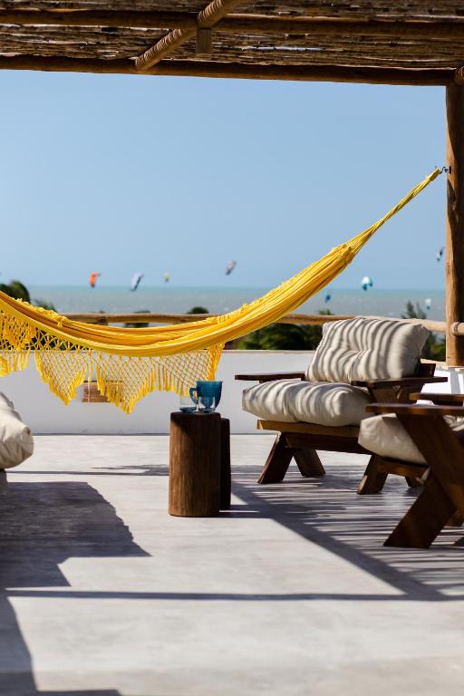 a hammock and chairs on a patio at Villa Aura, piscina privativa e rooftop com vista excepcional pro mar, 150m do mar e do Rancho do Kite, Praia do Prea in Prea