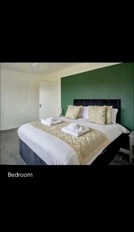 a bedroom with a large bed with a green wall at Spacious 3 bedroom house in nottingham in Nottingham