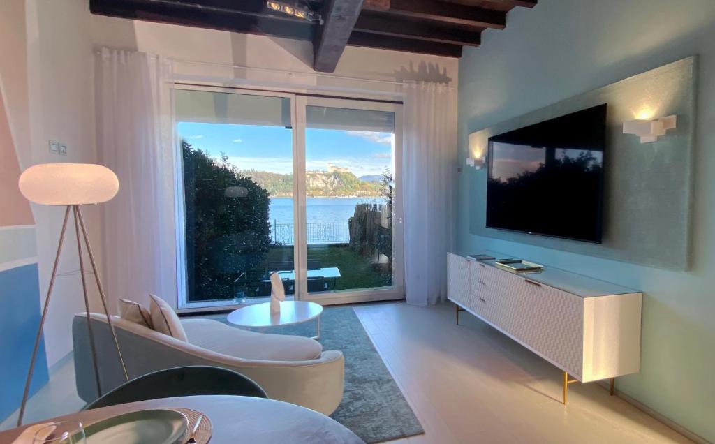 ein Wohnzimmer mit einem großen Fenster und einem TV in der Unterkunft FWL Italian Romance on the Lake in Arona