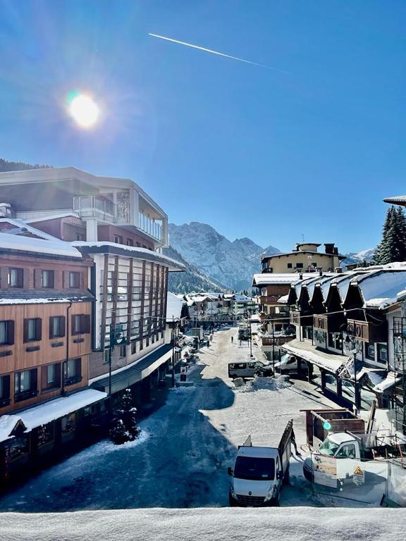 a snow covered street with buildings and cars parked at Sweet Campiglio in Madonna di Campiglio