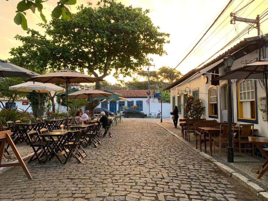 een patio met tafels, stoelen en parasols bij Cantinho da paz in Cabo Frio