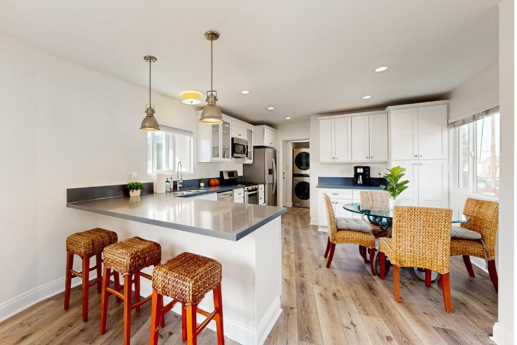 eine Küche mit weißen Schränken und einem Tisch und Stühlen in der Unterkunft The Cliffside Bungalow in San Diego