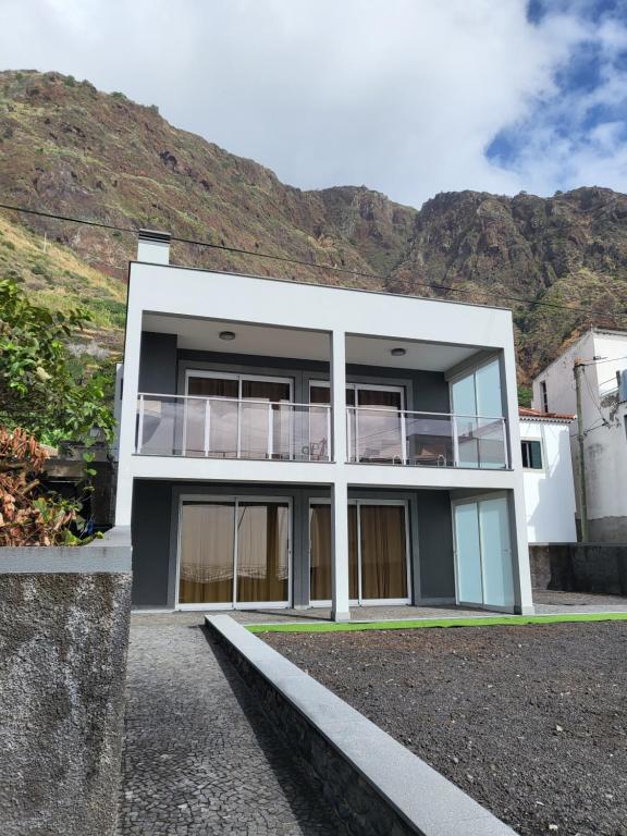 a white house with a mountain in the background at Casa Marcelino Refugio Frente Mar in Paul do Mar