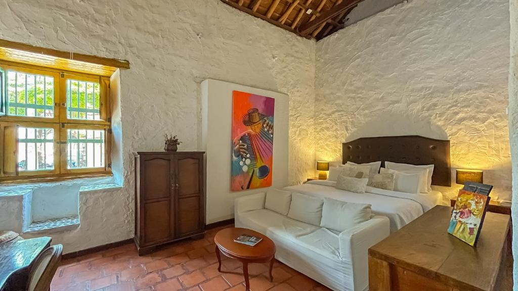 a bedroom with a bed and a couch and a table at Hotel Boutique Casa de Los Santos Reyes Valledupar in Valledupar