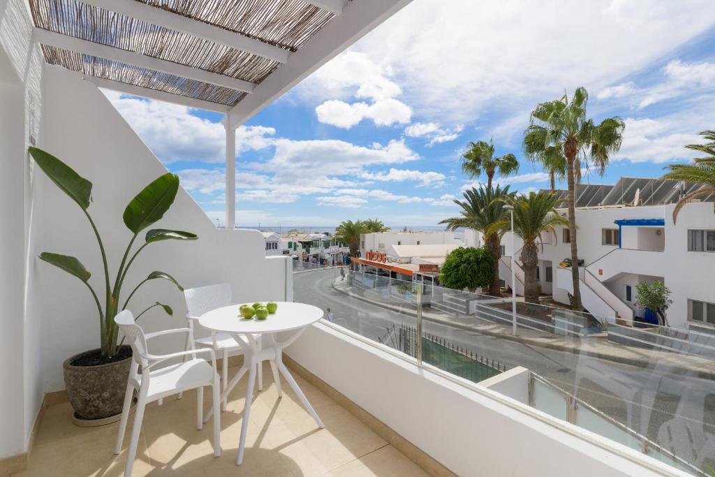 een balkon met een tafel en stoelen en uitzicht op de straat bij Casa Anzuelo, Puerto del Carmen in Puerto del Carmen