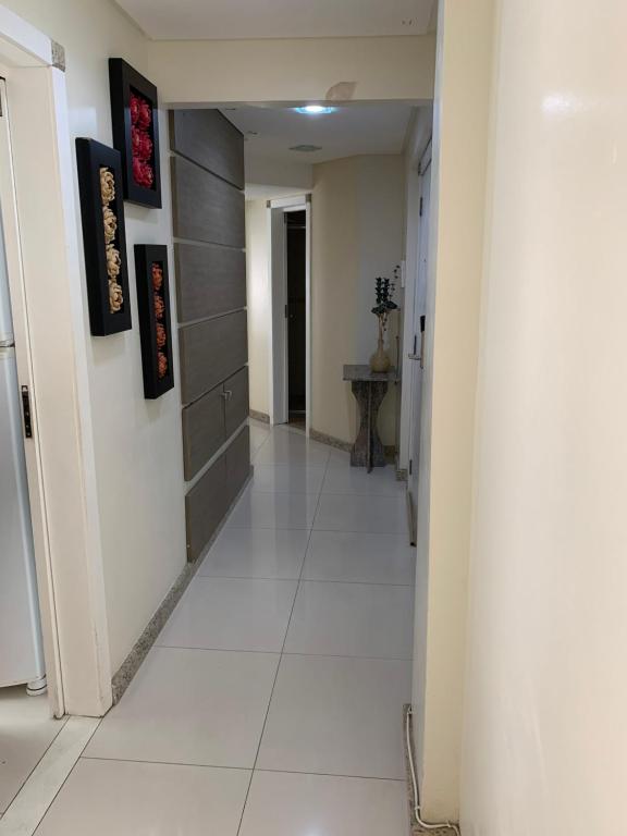 a hallway with a white tile floor and a white hallway at Pe na areia frente mar in Balneário Camboriú