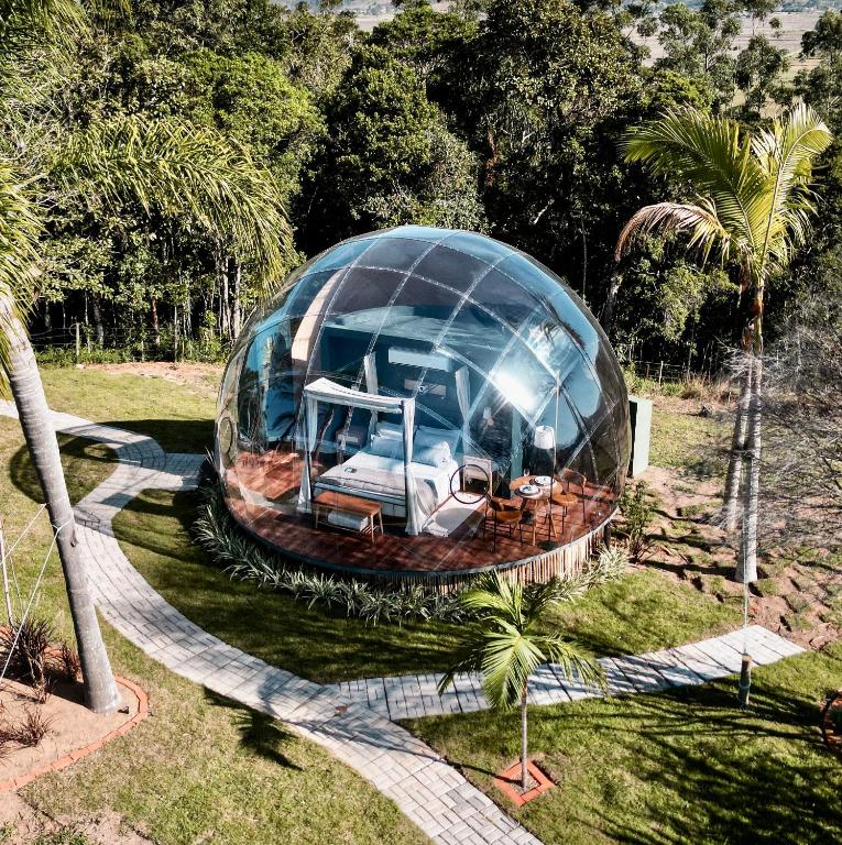 a glass dome in a field with a house at Refúgio Vista da Montanha in Imaruí