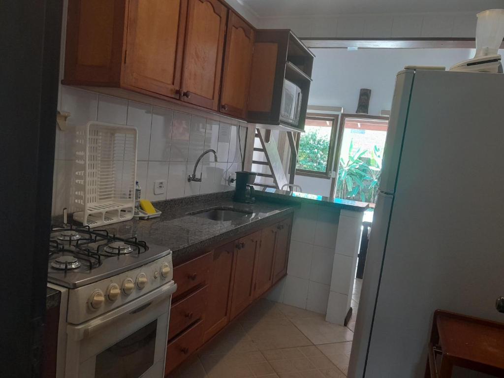 La cuisine est équipée d'une cuisinière, d'un évier et d'un réfrigérateur. dans l'établissement Casa Chales Família Reis, à Ilhabela