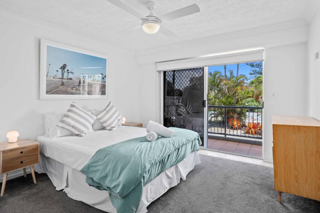 Dormitorio blanco con cama y ventana grande en Bilinga Beach House, en Gold Coast