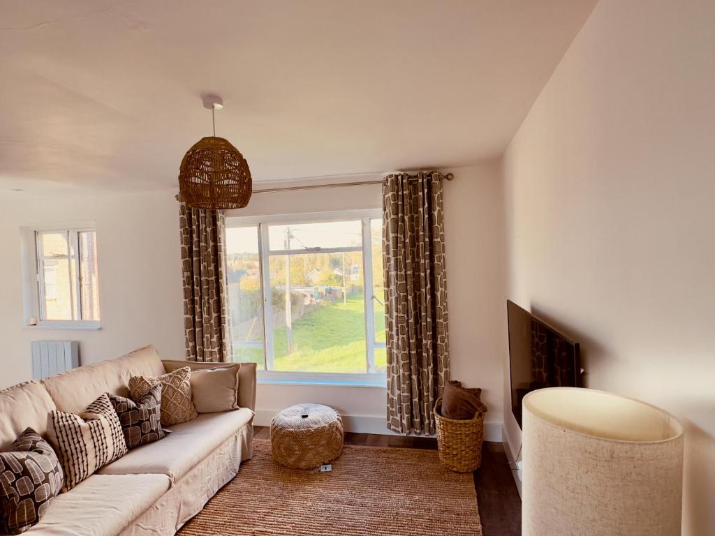 a living room with a couch and a window at Chic Barn Conversion in the Cotwolds in Enstone