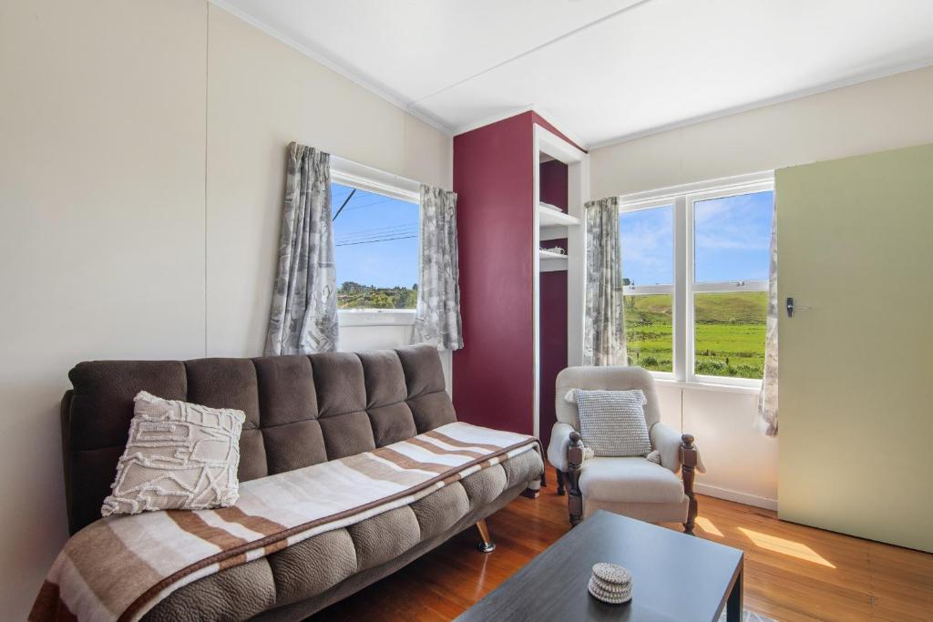 uma sala de estar com um sofá e uma cadeira em Pickers Cottage - Mapua Holiday Unit em Upper Moutere