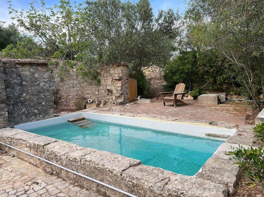 uma piscina em frente a uma parede de pedra em Top of The Hill em Moncarapacho
