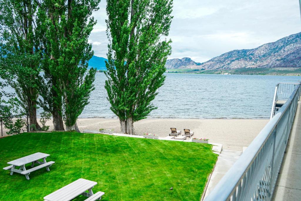 a park with benches and a beach and water at Poplars Motel on the lake in Osoyoos