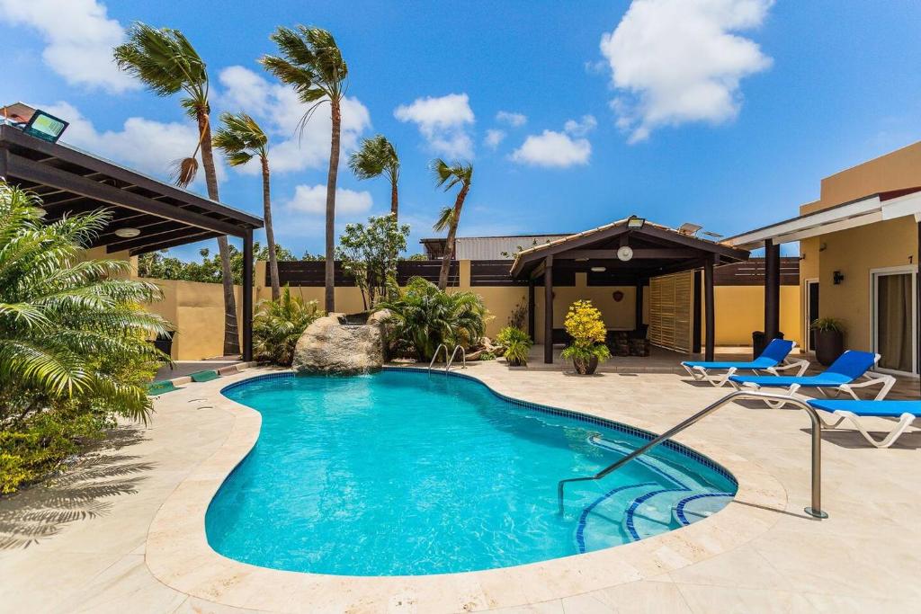 a swimming pool in a yard with chairs and a house at Juanedu Suites in Oranjestad