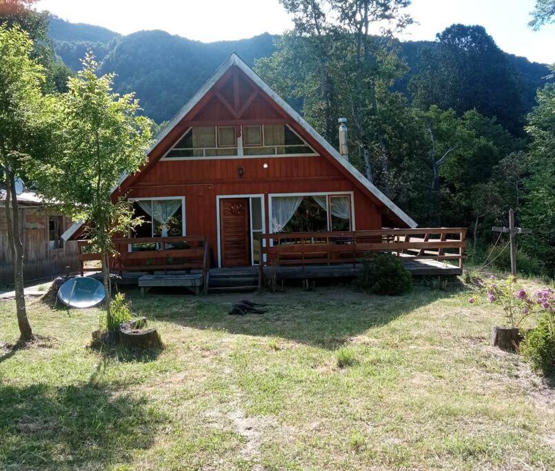 una casa roja con una valla y un patio en Casa en Liquiñe, en Liquiñe